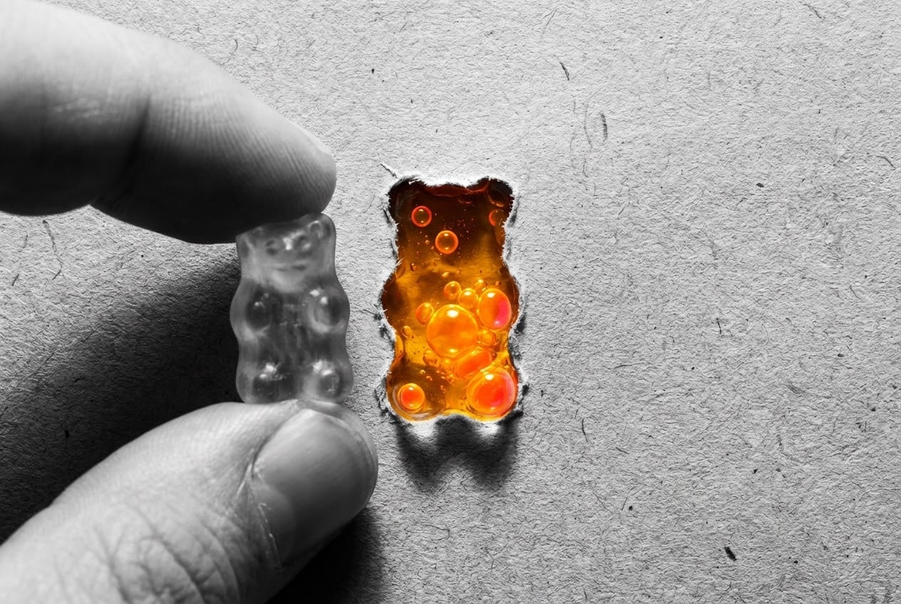 Artistic collage showing a hand holding a gummy bear with a cutout revealing boiling liquid, visualizing the instability risks in the thca vs cbd debate.